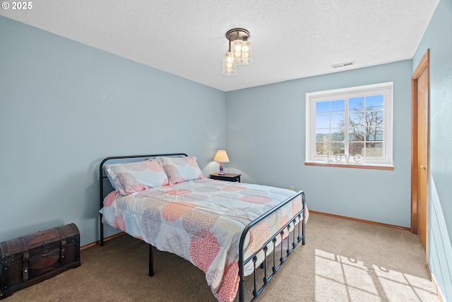 bedroom featuring visible vents, a textured ceiling, baseboards, and carpet floors