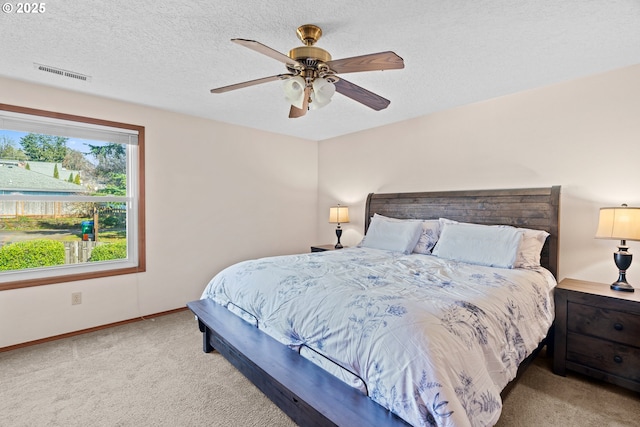 carpeted bedroom with visible vents, a textured ceiling, baseboards, and a ceiling fan