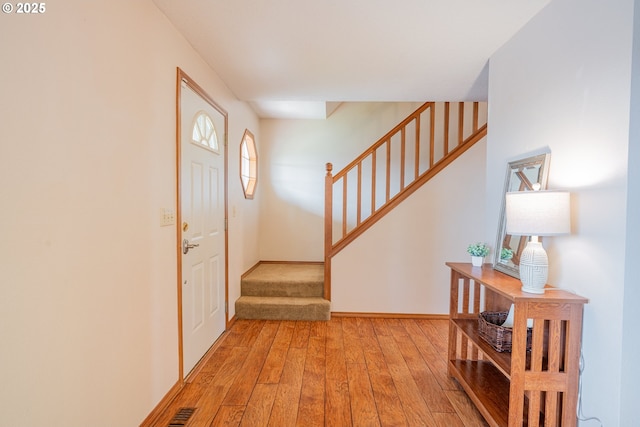 entrance foyer featuring visible vents, baseboards, light wood-style floors, and stairs