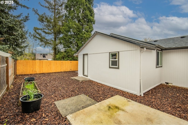 view of property exterior featuring a fenced backyard, roof with shingles, and a patio area