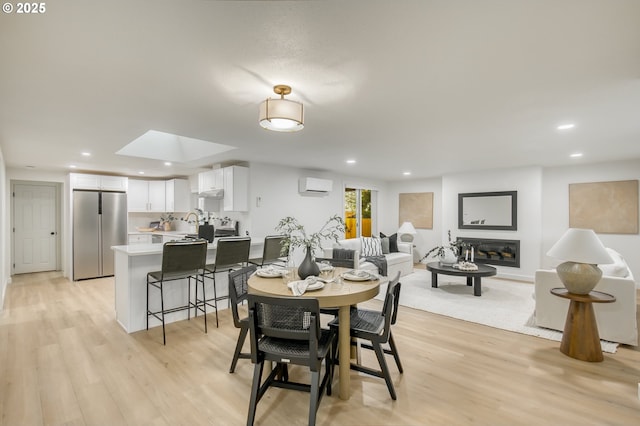 dining space featuring a skylight, light wood-style flooring, recessed lighting, and a wall mounted air conditioner