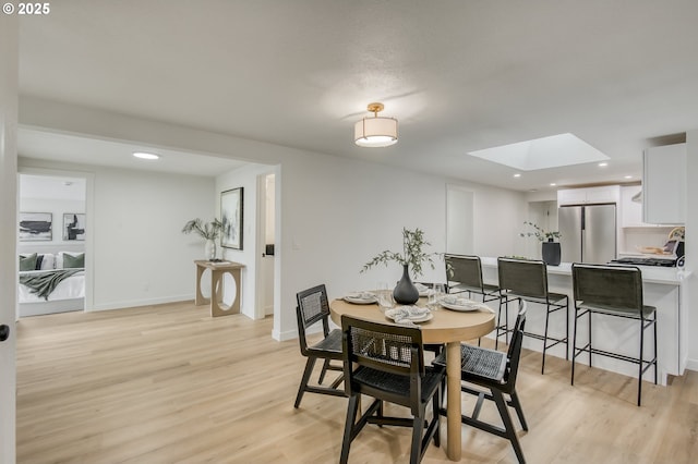 dining room with recessed lighting, baseboards, light wood-style floors, and a skylight