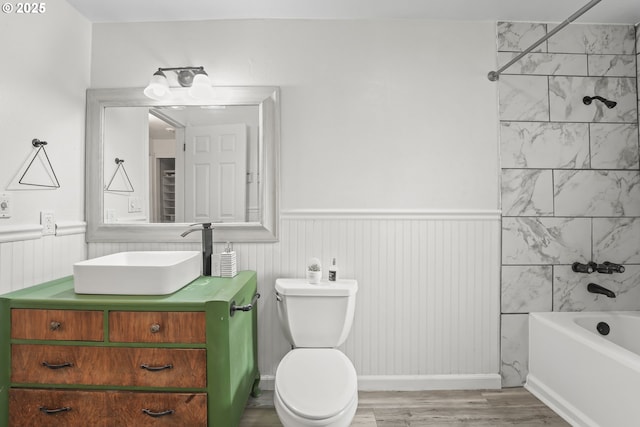 full bathroom featuring hardwood / wood-style floors, tiled shower / bath combo, toilet, and vanity