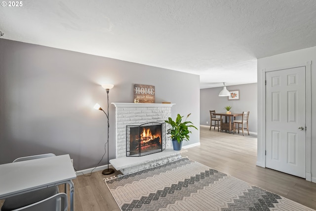 living room featuring a textured ceiling, hardwood / wood-style flooring, and a brick fireplace