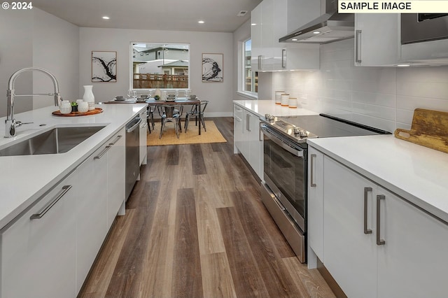 16755 SE Shimmering Leaf St, Happy Valley, OR 97086 - kitchen with modern cabinets, dark wood-style floors, wall chimney exhaust hood, a sink, and appliances with stainless steel finishes