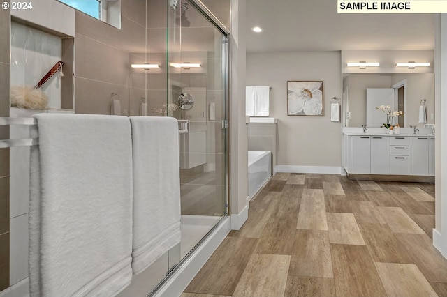 16755 SE Shimmering Leaf St, Happy Valley, OR 97086 - bathroom featuring a garden tub, vanity, wood finished floors, baseboards, and a shower stall