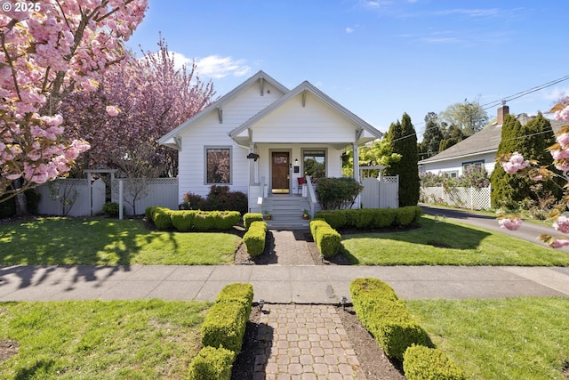 bungalow featuring a porch, a front lawn, and fence