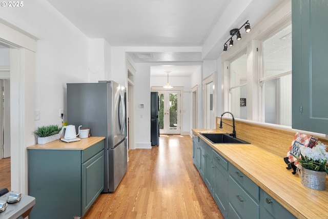 kitchen with a sink, light wood-style floors, freestanding refrigerator, and butcher block countertops