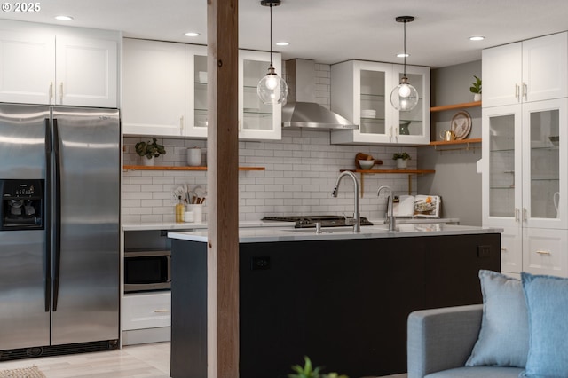 kitchen with wall chimney range hood, light countertops, stainless steel appliances, white cabinetry, and open shelves