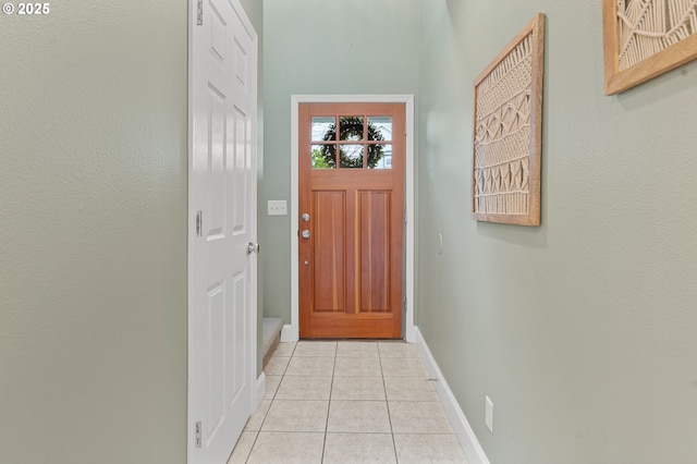 doorway with light tile patterned floors and baseboards