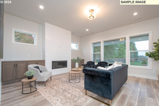 living room featuring a fireplace, recessed lighting, visible vents, light wood-type flooring, and baseboards