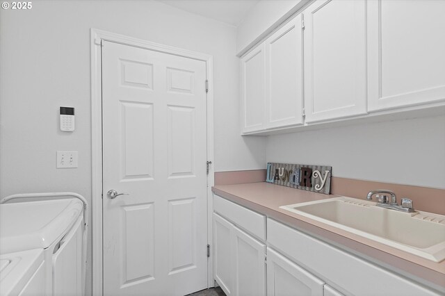 laundry room with cabinets, washer and clothes dryer, and sink