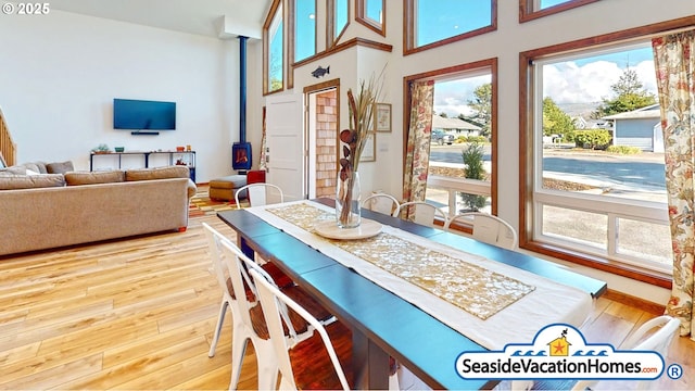 1560 S Edgewood St, Seaside, OR 97138 - dining space with healthy amount of natural light, hardwood / wood-style flooring, a wood stove, and a high ceiling