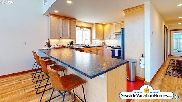 1560 S Edgewood St, Seaside, OR 97138 - kitchen featuring stainless steel range oven, light wood-style flooring, dark countertops, a breakfast bar area, and recessed lighting