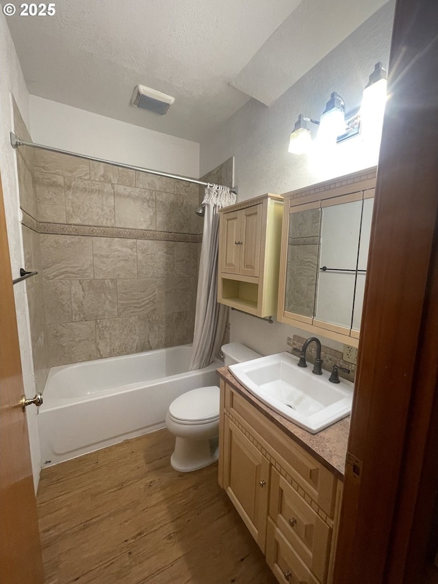 full bathroom with toilet, a textured ceiling, vanity, shower / bathtub combination with curtain, and hardwood / wood-style flooring