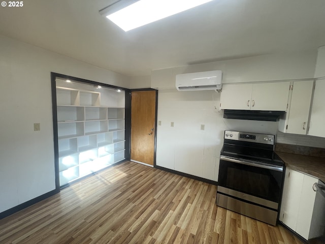 kitchen featuring white cabinetry, stainless steel range with electric cooktop, light hardwood / wood-style floors, and a wall mounted AC