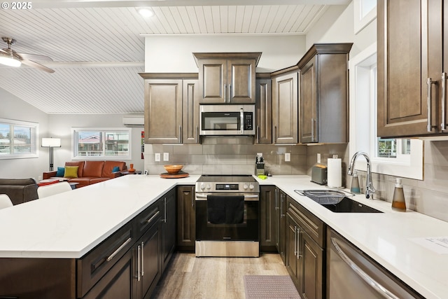 kitchen with an AC wall unit, sink, light wood-type flooring, dark brown cabinets, and stainless steel appliances