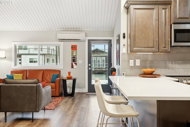 kitchen featuring a wall mounted air conditioner, tasteful backsplash, stove, wood-type flooring, and a kitchen bar