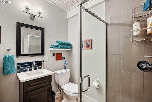 bathroom featuring backsplash, vanity, an enclosed shower, and toilet