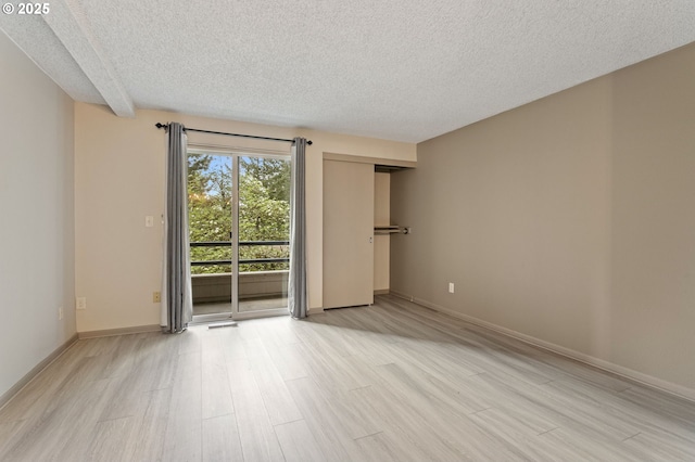 unfurnished room with light wood-type flooring, a textured ceiling, and baseboards