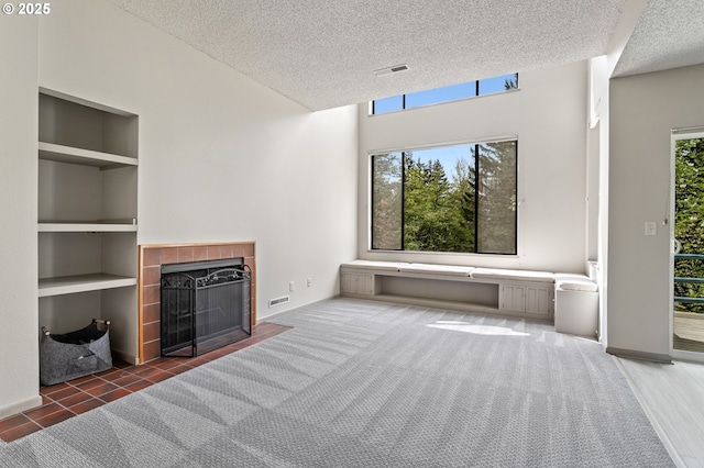 unfurnished living room with a textured ceiling, visible vents, built in features, a fireplace, and baseboards