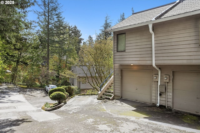 view of property exterior with stairway and a garage