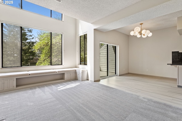 unfurnished living room with a textured ceiling, an inviting chandelier, and light wood-type flooring