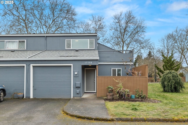 townhome / multi-family property with a garage, a front lawn, aphalt driveway, and roof with shingles