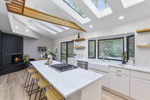 kitchen featuring sink, stainless steel appliances, white cabinets, and light stone counters