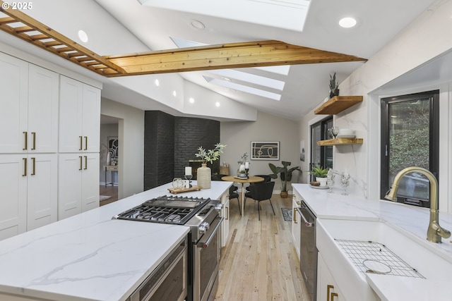 kitchen with sink, white cabinets, light stone counters, and appliances with stainless steel finishes