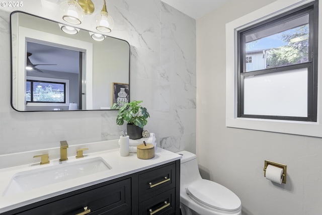 bathroom with toilet, vanity, and ceiling fan