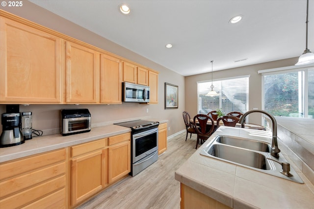 kitchen featuring light wood finished floors, recessed lighting, a sink, light brown cabinetry, and appliances with stainless steel finishes