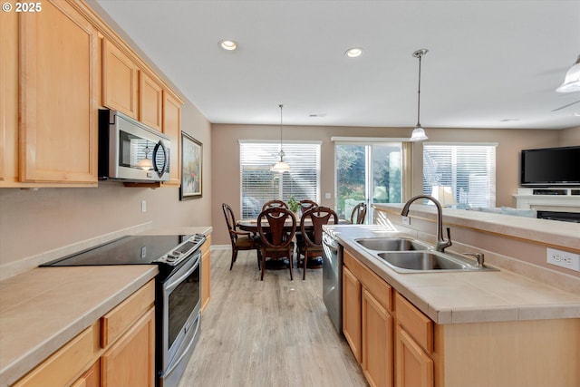 kitchen with light wood finished floors, recessed lighting, a sink, light brown cabinetry, and stainless steel appliances