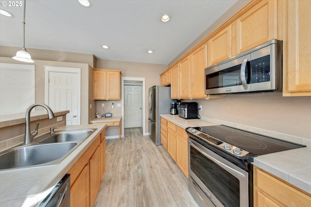 kitchen featuring a sink, light wood-style floors, light brown cabinetry, and stainless steel appliances