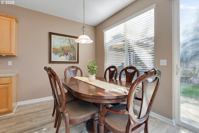 dining space with baseboards and light wood finished floors