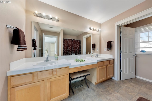 bathroom with double vanity, visible vents, baseboards, and a sink