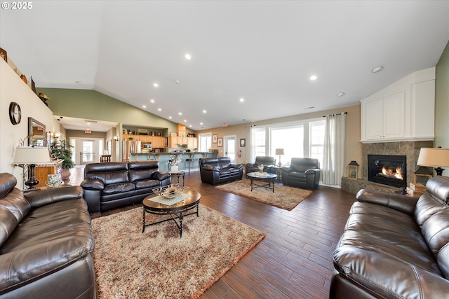 living room featuring dark wood-style floors, plenty of natural light, a fireplace, and vaulted ceiling