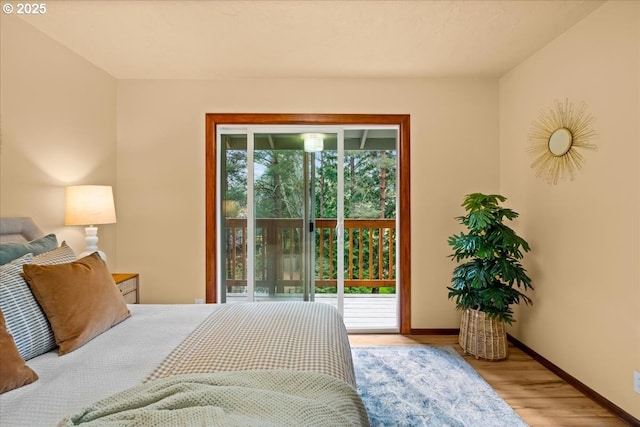 bedroom with access to exterior, wood finished floors, and baseboards