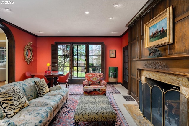 living room with crown molding, baseboards, arched walkways, recessed lighting, and a premium fireplace