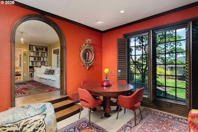 dining space with arched walkways, built in shelves, crown molding, and a textured wall