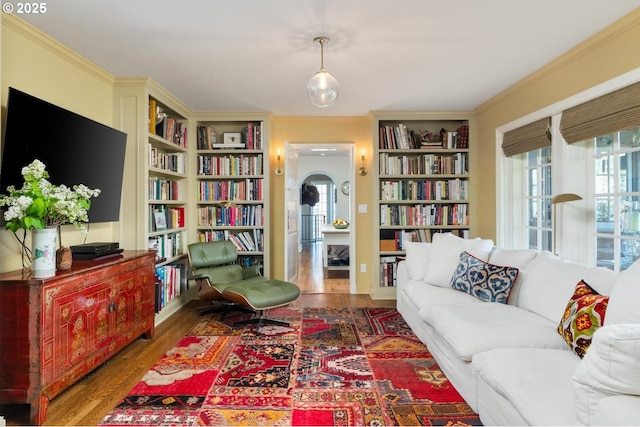 sitting room featuring built in shelves, wood finished floors, and plenty of natural light