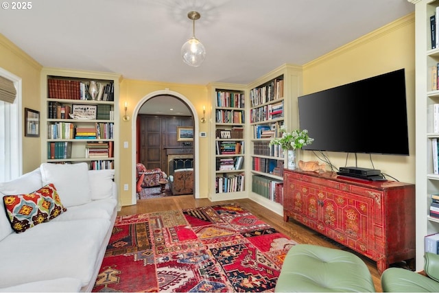 living area featuring arched walkways, built in shelves, and wood finished floors