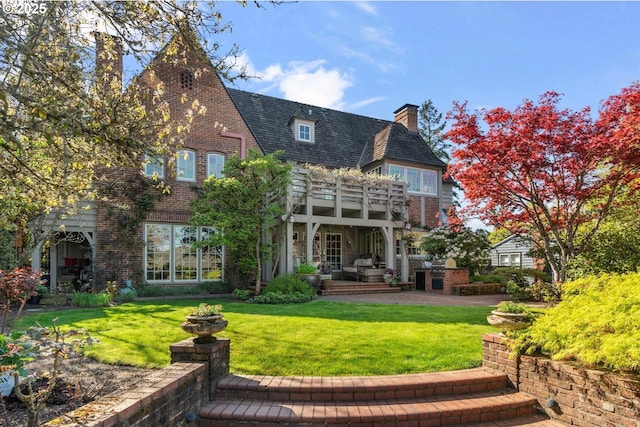 back of house featuring a chimney, brick siding, and a lawn