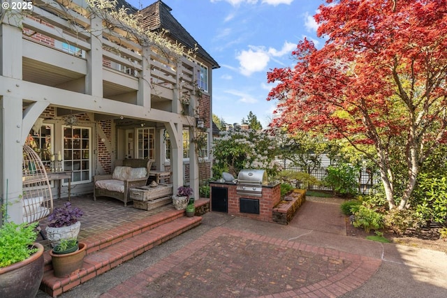 view of patio with fence, exterior kitchen, area for grilling, and a balcony
