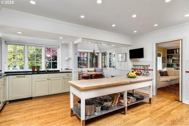 kitchen with light wood-style flooring, open shelves, ornamental molding, dark countertops, and a sink