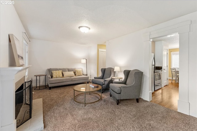 carpeted living area with a fireplace with raised hearth and a textured ceiling