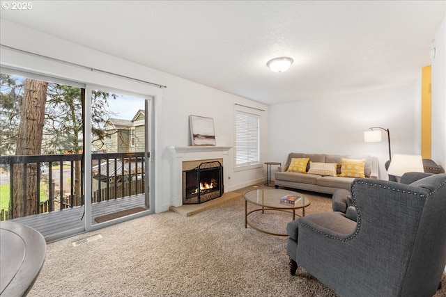 living room featuring baseboards, visible vents, carpet floors, a warm lit fireplace, and a textured ceiling