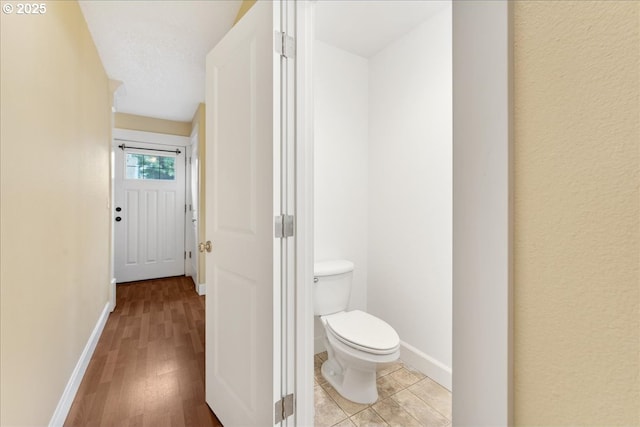 bathroom featuring toilet, wood finished floors, and baseboards