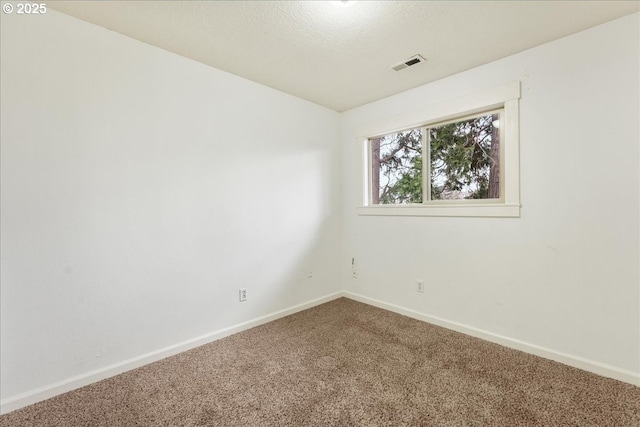 carpeted empty room featuring visible vents, a textured ceiling, and baseboards