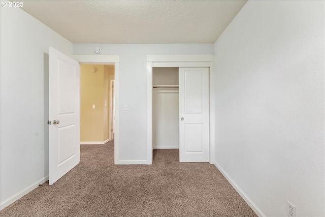 unfurnished bedroom with carpet flooring, baseboards, a closet, and a textured ceiling